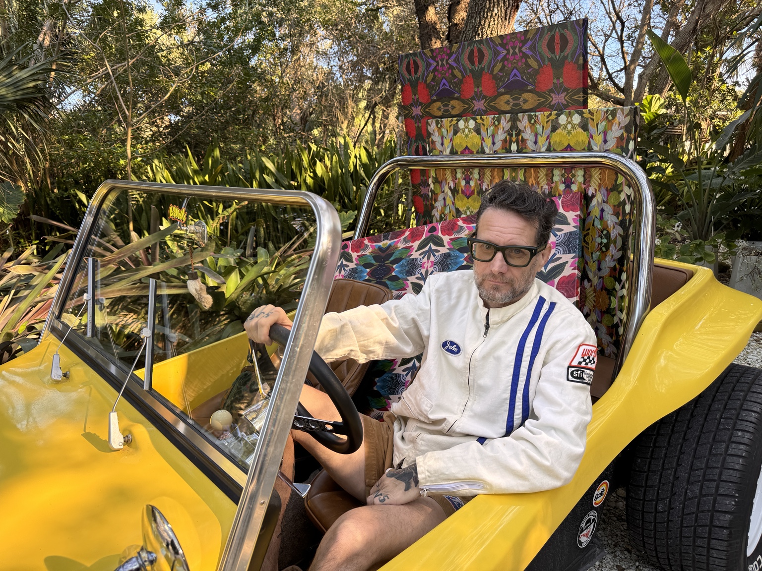 John in his yellow dune buggy in a lush Vero garden