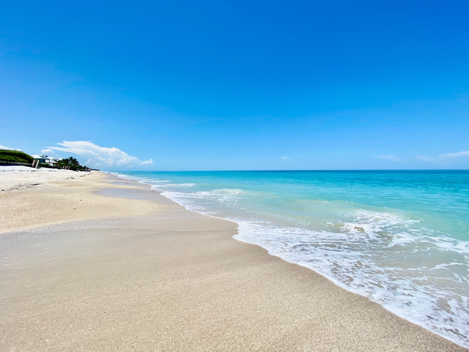 Turquoise water meeting a wide sandy Vero beach